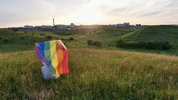 Gökyüzü arka planında LGBT bayrağı olan bir kadın - Fotoğraf, Görsel