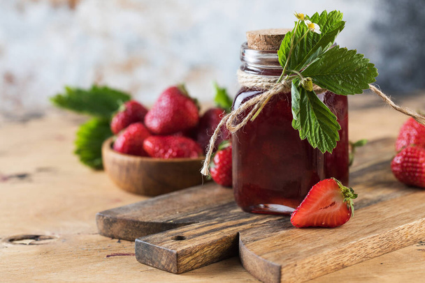 Strawberry jam in a jar on a wooden board. Fermented berries. Copy space. - Photo, image