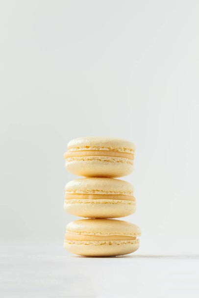 Stack of yellow macaroons with shallow depth of field on the white background. French sweet dessert cookies. - Fotoğraf, Görsel