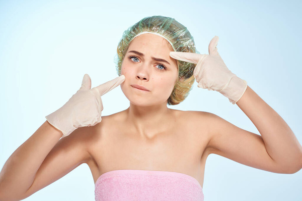 Frau mit nackten Schultern Duschkappen quetschen Pickel im Gesicht blauer Hintergrund - Foto, Bild