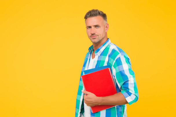 adult man student holding notebooks. man with folder yellow background. Businessman hold book for notes. guy has notepad for writing. handsome school or university teacher. copy space - Fotoğraf, Görsel
