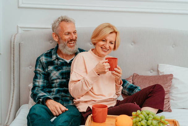 Mann und Frau frühstücken auf dem Bett mit Kaffee und Obst - Foto, Bild