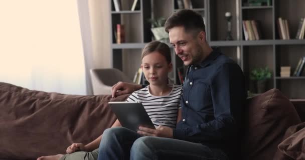 Young loving father and daughter using digital tablet together - Кадри, відео
