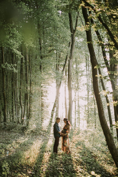 Pregnant woman and handsome man, standing face to face, walking in the forest - Foto, immagini
