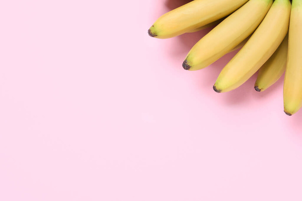 Bunch of ripe baby bananas on pink background, top view. Space for text - Foto, Bild