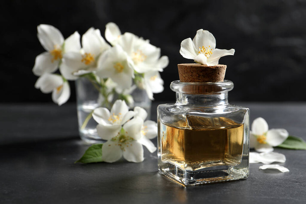 Jasmine essential oil and fresh flowers on dark grey table, space for text - Fotografie, Obrázek