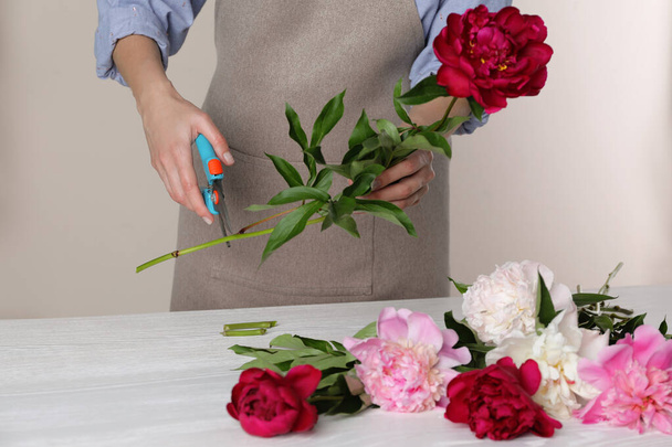 Florist cutting flower stem with pruner at workplace, closeup - 写真・画像