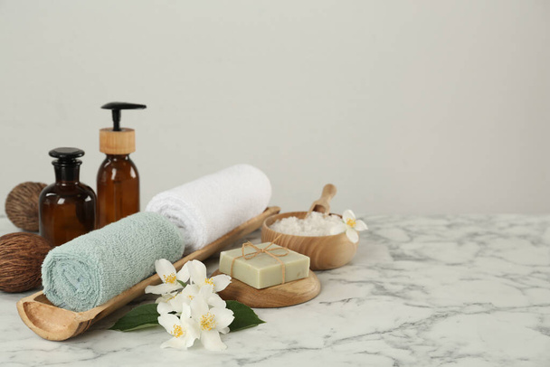 Composition with beautiful jasmine flowers and skin care products on white marble table, space for text - Fotoğraf, Görsel