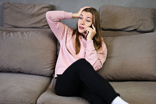 Portrait of cute caucasian girl talking phone at home while sitting on couch - Foto, Imagem