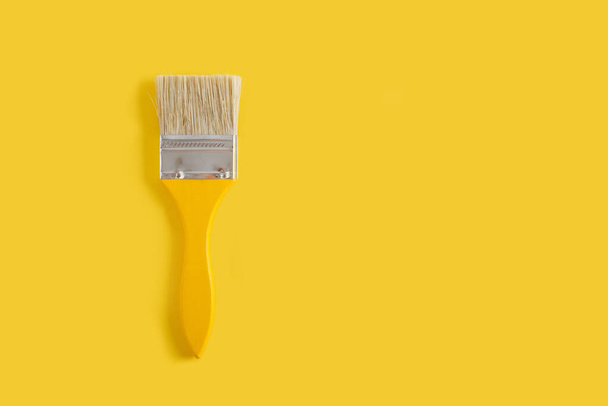 wooden yellow paint brushes on a yellow background copy space top view - Foto, imagen
