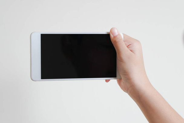 Obchodní koncept: Mladý muž držící smartphone s prázdnou obrazovkou na bílém pozadí, detailní záběr ruky, reklamní text prodávající marketingové produkty, maketa up, Prostor pro text. - Fotografie, Obrázek