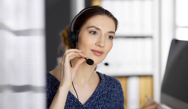 Asian or Latin american businesswoman talking by headset while sitting in office. Call center and diverse people group in business - Valokuva, kuva