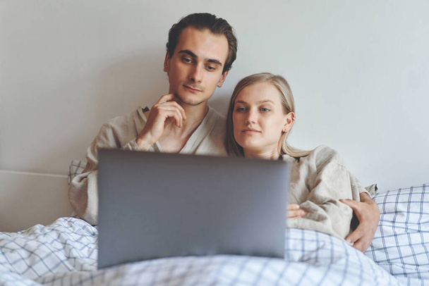 Front view of focused couple with laptop at bed - Foto, immagini