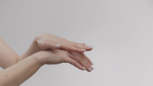 Lady alkalmazó kényeztető kéz krém és dörzsölés tenyér, védi a bőrt a napbarnított, oldalnézet, lassított felvétel, üres tér - Felvétel, videó
