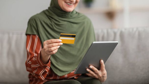 デジタルタブレットとクレジットカードの屋内を使用して認識できないイスラム教徒の女性 - 写真・画像