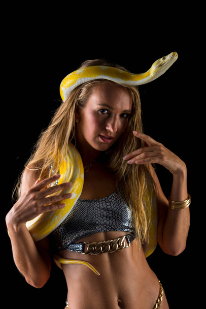 Een prachtig blond model poseert met een Boa slang in een studio omgeving - Foto, afbeelding