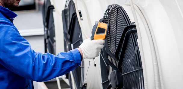 Technician uses a thermal imaging infrared thermometer to check the condensing unit heat exchanger. - Fotografie, Obrázek