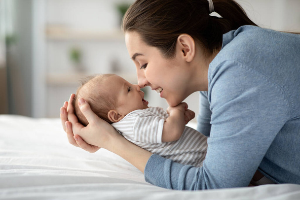 Fyzický kontakt s kojencem. Šťastná maminka dotýkání nosy se svým novorozeným dítětem - Fotografie, Obrázek