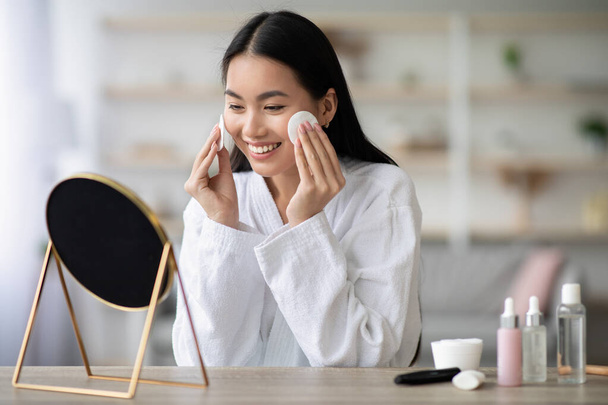 Csinos ázsiai nő tisztítja az arcát tonerrel - Fotó, kép