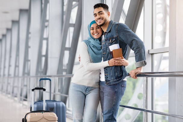 Щасливі люблячі мусульманські подружжя приймають в терміналі аеропорту під час очікування польоту
 - Фото, зображення