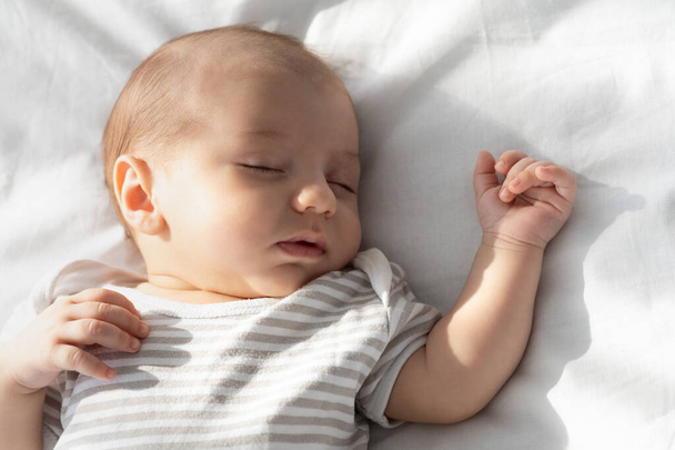 Dagslaaptijd. Closeup portret van schattige kleine pasgeboren baby slapen op bed - Foto, afbeelding