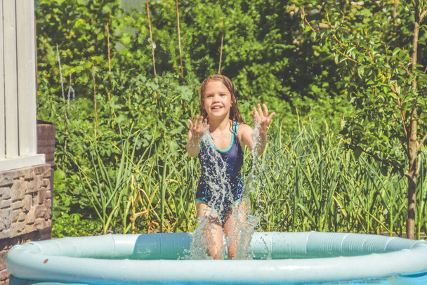 a girl child is splashing in the pool on the street - Φωτογραφία, εικόνα