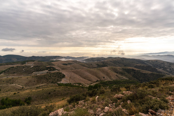 bergachtig landschap in Zuid-Spanje, er zijn bomen en struiken op de berg, de lucht heeft wolken - Foto, afbeelding