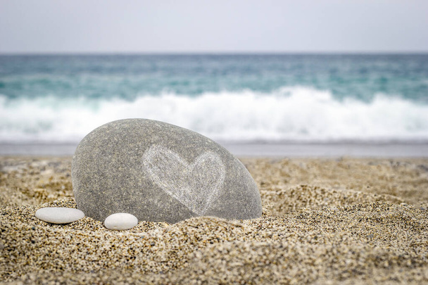海の砂の上にハートマークのついた石 - 写真・画像