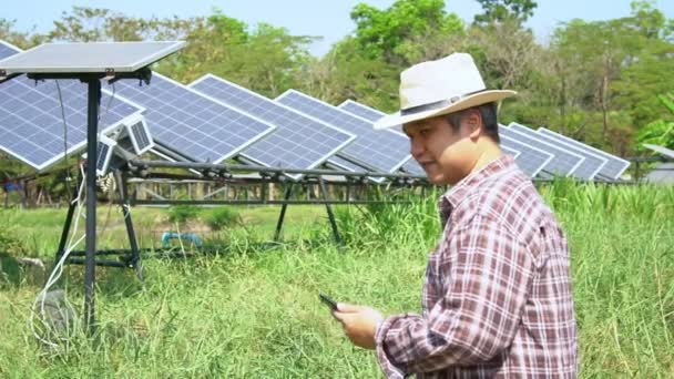 Gli agricoltori asiatici usano gli smartphone per regolare il grado delle celle solari e controllare le prestazioni delle celle solari dopo la pioggia e le macchie di polvere e sporcizia sulla cella solare. Concetto di tecnologia agricola. Girato al rallentatore. - Filmati, video