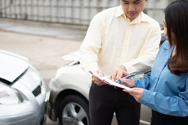 Ázsiai női sofőr Beszéljen Biztosítási ügynökkel a sérült autó és az ügyfél ellenőrzéséről a balesetet követő bejelentési űrlapon. A biztosítás és az autóbalesetek fogalma. - Fotó, kép