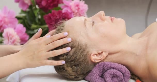 Młoda kobieta otrzymuje masaż głowy w centrum spa. Masseuse robi relaksujący masaż głowy w centrum wellness.  - Materiał filmowy, wideo