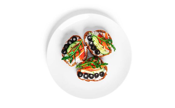 Bruschetta with cream cheese, salmon and vegetables isolated on a white background. Toasts isolated. Sandwich isolated. Sandwich with salmon and cheese. - Photo, Image