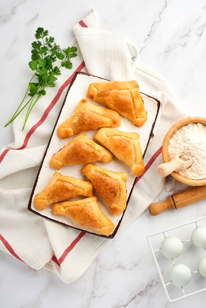 Fried empanadas with cilantro, meat, egg, tomato and chili sauce on white background. Latin American and Chilean independence day concept. - Foto, afbeelding