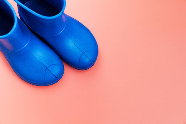 blaue Gummistiefel auf rosa Hintergrund. Schuhe für Regenwetter und Pfützen. Schuhgeschäft. schützen Sie Ihre Füße vor Feuchtigkeit und Schmutz. Kopierraum. - Foto, Bild