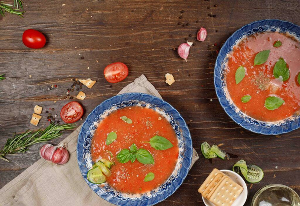 Espanjalaista ruokaa. Kylmää keittoa tomaattia, kurkkua ja paprikaa. Se virkistää lämpöä ja sammuttaa janon. Kaksi lautasellista tomaattikeittoa puupöydällä. Flatlay ja kopio tilasta - Valokuva, kuva