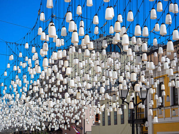 beaucoup de lampes blanches pendent au-dessus de la rue. Illumination et décoration de la rue. - Photo, image