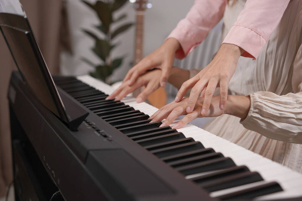 Duetto donne adulte suonano il pianoforte elettronico con foglio note. Newby pianista praticare e imparare a suonare la canzone insieme come duo - Foto, immagini