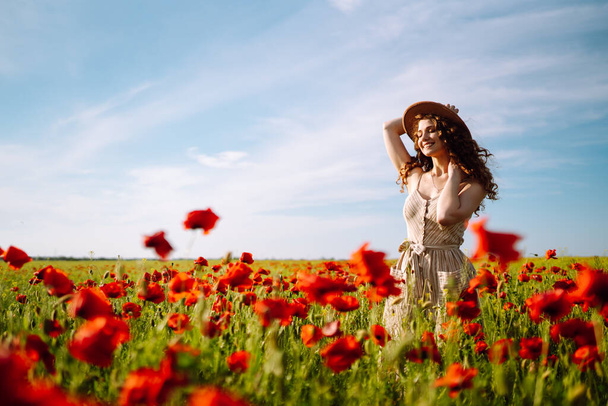 Beautiful woman in a blooming poppy field. People, lifestyle, travel, nature and vacations concept. - Fotó, kép