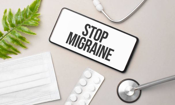 stop migraine word on smartphone,stethoscope and green plant - Foto, Imagen