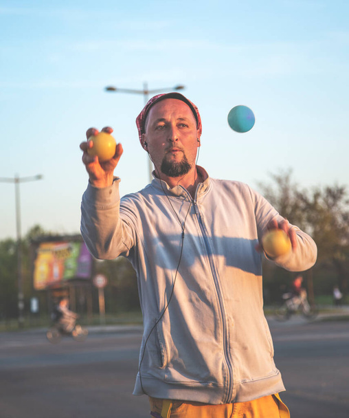 Un jongleur qui travaille dans la circulation. Juggler homme performant aux feux de circulation, après la présentation, il demande aux conducteurs pour un don. - Photo, image