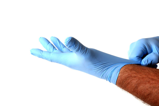 Medizinische Handschuhe.Zwei blaue OP-Handschuhe. isoliert auf weiß. Gummihandschuh. Die menschliche Hand trägt einen Latexhandschuh. Arzt oder Krankenschwester ziehen Schutzhandschuhe an. Medizinische Nitrilhandschuhe. Schneideweg. Raum für Text.  - Foto, Bild