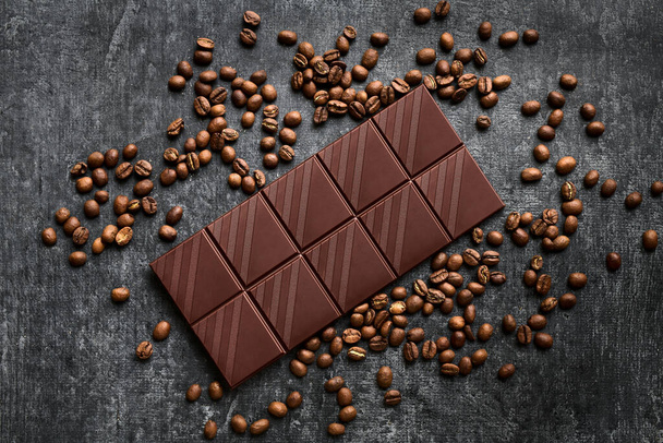 Chocolate bar in a scattering of coffee beans, dark, top view, close up - Фото, зображення