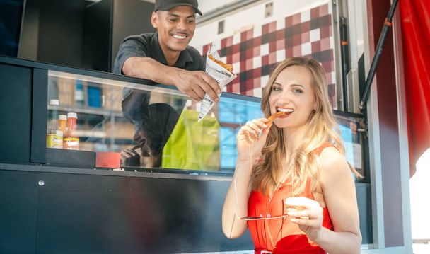 Beautiful woman ordering fries at a food truck - Photo, Image
