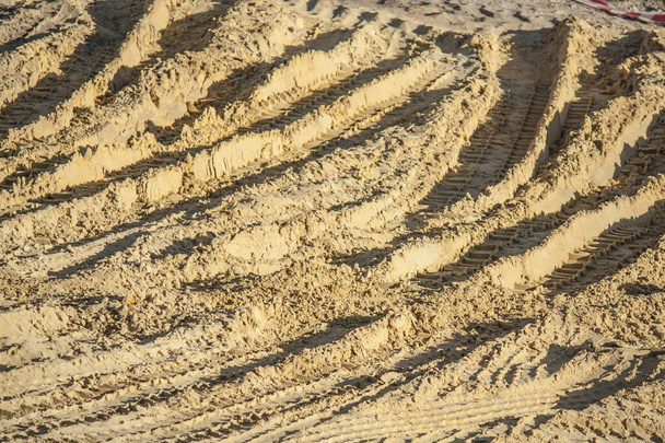 Следы строительной техники на желтом песке вблизи - Фото, изображение