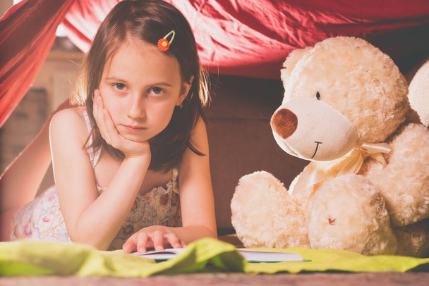 Retrato de una joven hermosa leyendo un libro grande. Cerca se encuentra un oso de peluche. Imagen horizontal. - Foto, imagen