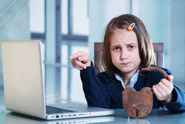 Sad business child girl having problem with pc laptop. She holding open lock as symbol of trouble with internet security, antivirus protection, online scam, fatal error. - Photo, Image