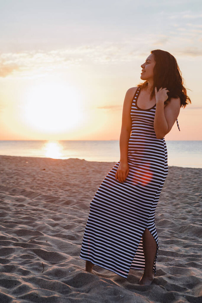 young beautiful sexy woman in dress walking bay sandy beach at sunset. summer vacation - Zdjęcie, obraz