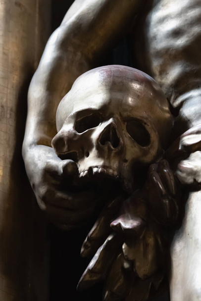 Фрагмент древней статуи Адама с человеческим черепом в качестве символа первых людей в Эдем Райском саду. Вертикальное изображение. - Фото, изображение