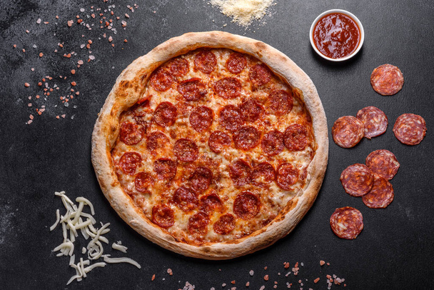 Pizza soslu Pepperoni pizza, mozzarella peyniri ve pepperoni. İçinde malzemeler olan bir masada pizza. - Fotoğraf, Görsel
