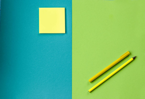 Minimális iskolai és irodai kellékek élénk zöld és türkiz háttérrel: toll, ceruza, jegyzetpapír. Koncepció: vissza az iskolába. Lapos, felülnézet. - Fotó, kép